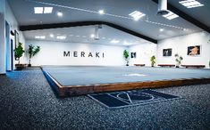 an empty room with a basketball court in the middle and plants on the wall behind it