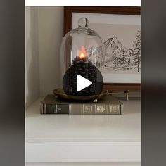 a clock sitting on top of a table under a glass dome with a lit candle in it