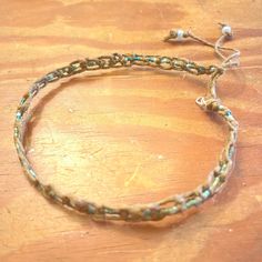 a close up of a bracelet on a wooden table with beads and chains attached to it