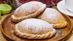 two pastries on a wooden plate next to limes and a cup of coffee