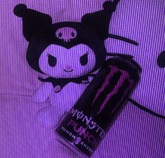 a purple background with a black and white cat stuffed animal next to an energy drink