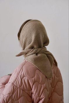 the back of a woman's head wearing a pink jacket and a beige scarf