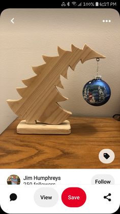 a wooden christmas tree ornament sitting on top of a table next to a cell phone