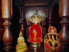 there is a small shrine in the middle of some wooden pillars with gold decorations around it