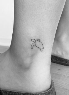 a black and white photo of a foot with a small turtle tattoo on the ankle