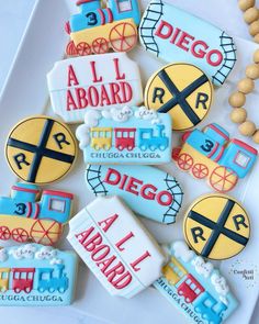 decorated cookies are arranged on a plate with the words all aboard and train tracks painted on them