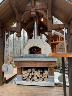 an outdoor pizza oven with logs in the foreground and wood on the other side