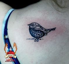 a small bird tattoo on the back of a woman's left shoulder and chest