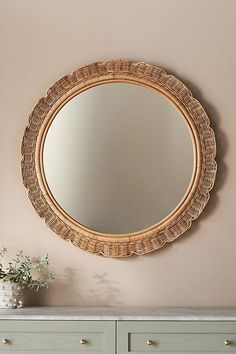 a round mirror hanging on the wall above a dresser