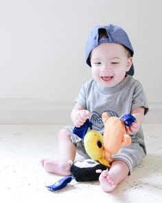 a small child sitting on the floor playing with a stuffed animal toy in his hands