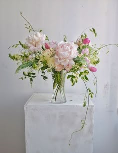 a vase filled with pink and white flowers on top of a table next to a wall