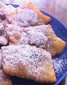 a blue plate topped with pastries covered in powdered sugar on top of a wooden table