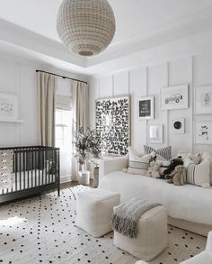 a living room with white furniture and black and white decor on the walls, along with a baby's crib