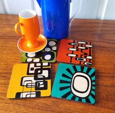 four coasters with different designs on them sitting on a table next to a blue trash can