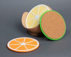 two orange slices and a cork coaster on a gray surface with one cut in half