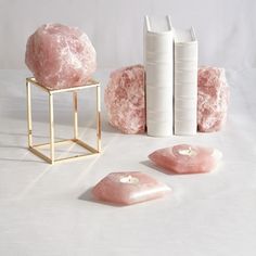 three pink rocks sitting on top of a table next to two white bookends