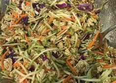 a bowl filled with shredded carrots, cabbage and other vegtables next to a spoon