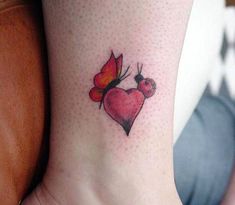 a small heart tattoo with a butterfly on the side of its leg and a red flower in the middle