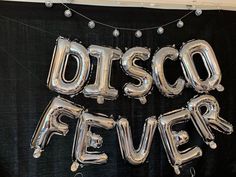 the words disco fever are made out of silver foil balloons on a black table cloth