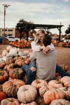 a man and woman sitting on top of pumpkins