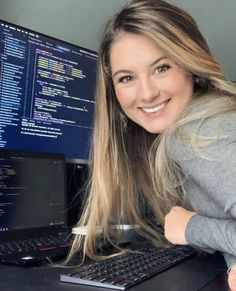 a woman sitting at a desk in front of a computer with code on the screen