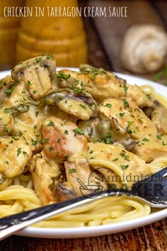 chicken in tarragon cream sauce over pasta on a white plate with a fork