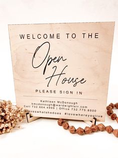 an open house sign sitting on top of a table next to some dried up flowers