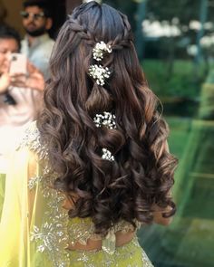 the back of a woman's head with long hair and flowers in her hair