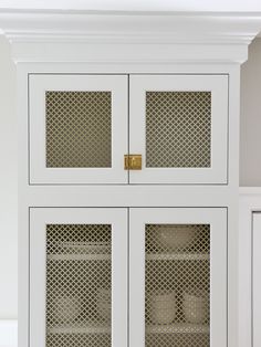 a white cabinet with glass doors and gold handles