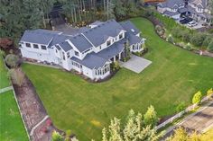 an aerial view of a large white house in the middle of a lush green yard