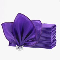 a stack of purple napkins sitting on top of each other next to a ring