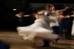 a blurry photo of people dancing in a dance hall with their arms around each other