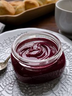 a spoon sitting on top of a white plate next to a jar of red liquid