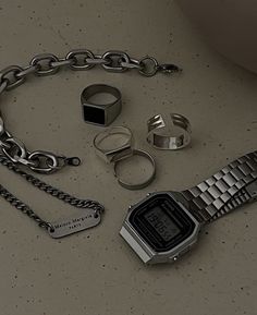 a bunch of different items that are laying on the ground together, including a watch and chain