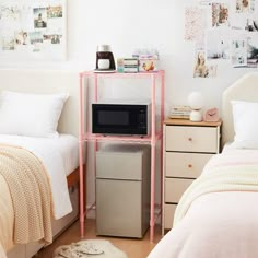 two twin beds in a small room with white sheets and pink accents, one has a microwave on the nightstand