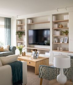 a living room filled with furniture and a flat screen tv mounted on a wall above a wooden coffee table