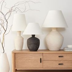 three lamps are sitting on a table next to a dresser