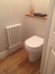 a white toilet sitting next to a radiator in a bathroom