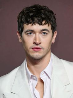 a close up of a person wearing a white suit and tie with his eyes wide open