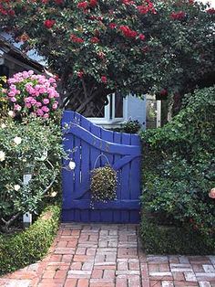 a blue gate surrounded by flowers and bushes