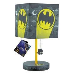 the batman lamp is on top of a stand with a card in front of it