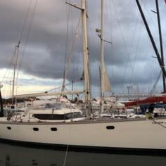 the sailboat is docked at the dock in the water with other boats around it