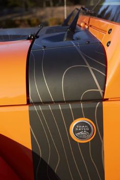 an orange sports car with black stripes on it