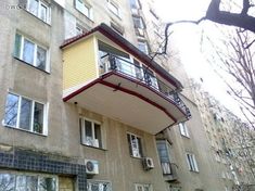 an apartment building with many windows and balconies on the second floor, in front of a tree