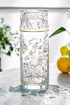 a glass vase sitting on top of a table next to lemons and a potted plant