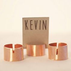 three rings sitting next to each other on top of a white surface with a sign that says kevin