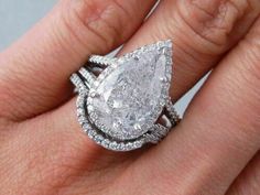 a woman's engagement ring with a pear shaped diamond in the center and two rows of diamonds on each band