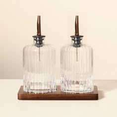 two clear glass bottles sitting on top of a wooden stand