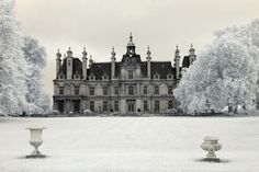 two urns in front of a large building with snow on the ground and trees