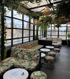 an outdoor seating area with lots of plants on the ceiling and tables in front of it